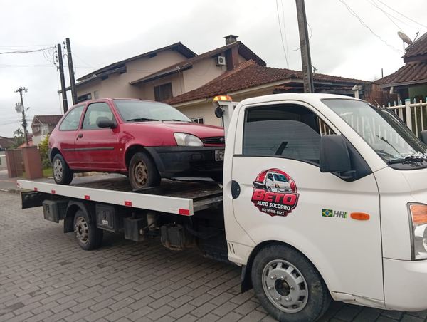 Guincho do Beto Auto Socorro com carro vermelho em cima, em rua de bairro
