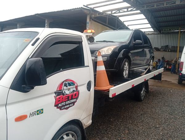 Guincho plataforma branco do Beto Auto Socorro com carro preto em cima, em pátio de Joinville